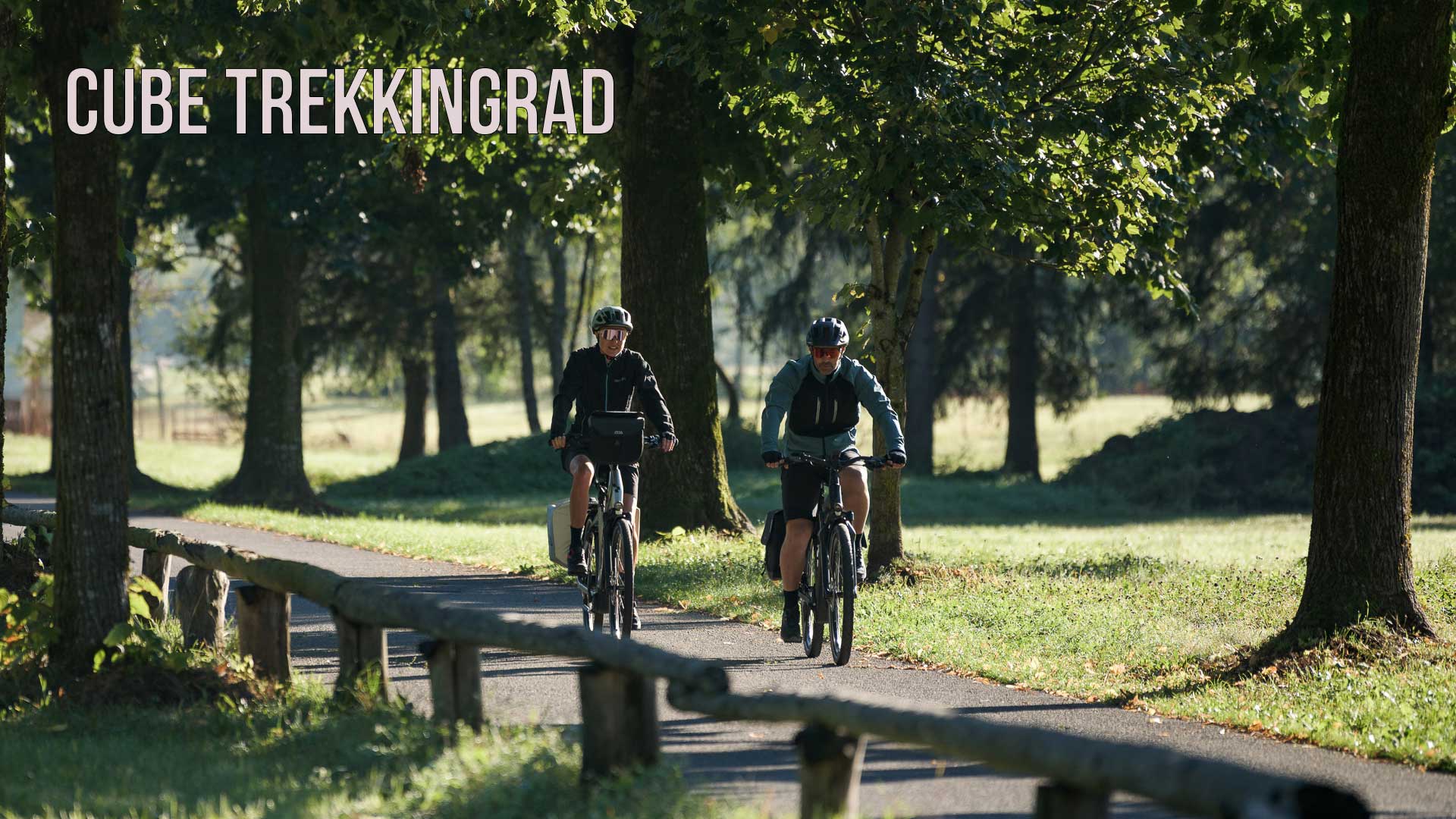 Si vede un'immagine con la scritta Cube Trekkingrad (bicicletta da trekking Cube), sulla quale è raffigurata una coppia che percorre una pista ciclabile in un parco.
