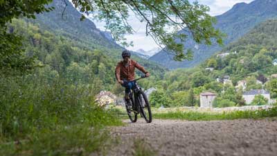 Un ciclista percorre con la sua mountain bike un sentiero sterrato, sullo sfondo si vede un paesaggio montuoso.