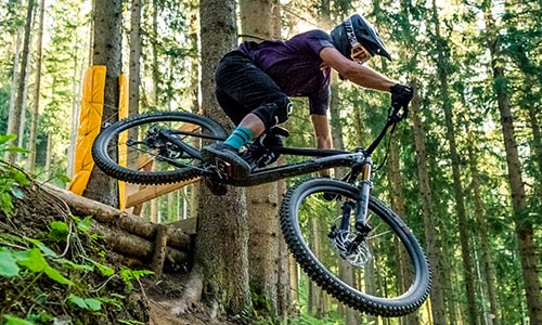 Ciclista salta nel bosco con una mountain bike full suspension.