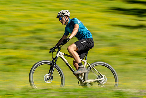Ciclista con maglietta blu e casco su una mountain bike hardtail Cube Reaction.