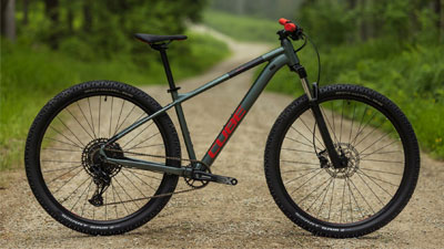 Si vede una mountain bike Cube grigia con dettagli rossi su una strada sterrata.